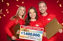 Drei Moderatoren zeigen einen Scheck in Höhe von 1,4 Millionen Euro
