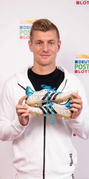 Toni Kroos hält Fußballschuhe in die Kamera